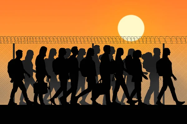 migranti che camminano lungo filo spinato